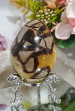 Load image into Gallery viewer, Septarian (Dragon Stone) Egg Crystal Carving Stone on Stand.
Grounds & Nurtures
Beautiful Polished Septarian Egg Crystal Carving on plastic stand. Has natural divits formations. Madagascar sourced.
Known as the Dragon Stone. Formed 70 million years ago from volcanic mud and sea life. These polished egg shaped feature cracked patterns of yellow Calcite, brown Aragonite and grey Limestone.The egg shape symbolises new beginnings, the "unfolding of energy from within,".