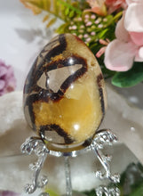 Load image into Gallery viewer, Septarian (Dragon Stone) Egg Crystal Carving Stone on Stand.
Grounds & Nurtures
Beautiful Polished Septarian Egg Crystal Carving on plastic stand. Has natural divits formations. Madagascar sourced.
Known as the Dragon Stone. Formed 70 million years ago from volcanic mud and sea life. These polished egg shaped feature cracked patterns of yellow Calcite, brown Aragonite and grey Limestone.The egg shape symbolises new beginnings, the "unfolding of energy from within,".