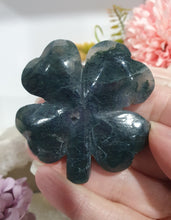 Load image into Gallery viewer, Beautiful polished Moss Agate Four Leaf Clover Crystal Carving on plastic stand. Insoires tranquility and grounding.
HAS A SMALL CRACK on front and a lovely druzy on back