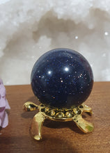 Load image into Gallery viewer, Blue Sandstone Sphere Crystal Carving on Gold Turtle Stand | Inspires Concentration and Courage
Beautiful Blue Sandstone Sphere Crystal Carving on Gold Stand in the shape of a turtle. This is so lovely and sparkly.