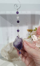 Load image into Gallery viewer, THE MYSTIC AWAKENING" Handcrafted Amethyst Raw Crystal Stone Silver Crystal Energy Enhancer© Hanger Ornament Suncatcher
INSPIRES INTUITION, WISDOM AND SPIRITUALITY
Stunning Raw Amethyst crystal stone beaded with Amethyst and Quartz. Wire wrapped in silver