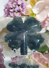 Load image into Gallery viewer, Beautiful polished Moss Agate Four Leaf Clover Crystal Carving on plastic stand. Insoires tranquility and grounding.
HAS A SMALL CRACK on front and a lovely druzy on back