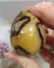 Load image into Gallery viewer, Septarian (Dragon Stone) Egg Crystal Carving Stone on Stand.
Grounds & Nurtures
Beautiful Polished Septarian Egg Crystal Carving on plastic stand. Has natural divits formations. Madagascar sourced.
Known as the Dragon Stone. Formed 70 million years ago from volcanic mud and sea life. These polished egg shaped feature cracked patterns of yellow Calcite, brown Aragonite and grey Limestone.The egg shape symbolises new beginnings, the "unfolding of energy from within,".