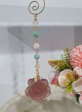 Load image into Gallery viewer, "THE BLUSHING ROSE" Strawberry Quartz Rose Carving gold Crystal Energy Enhancer© Hanger Ornament Suncatcher.
HAPPINESS / LOVE / HARMONY
"THE BLUSHING ROSE - Like the petals of a rose unfolding, The Blushing Rose encourages us to embrace self-love, joy and the beauty within."
Gorgeous Strawberry Quartz Rose Crystal Carving beaded with Ice Pink Malaysian Jade, Rose Quartz, Amazonite and Quartz. Wire wrapped in gold