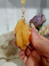 Load image into Gallery viewer, Stunning "ROSE OF SUNSHINE" Handcrafted Orange Calcite Rose Carving gold Crystal Energy Enhancer© Hanger Ornament Suncatcher. hang in your room or space. Inspires Joy, cleansing and love