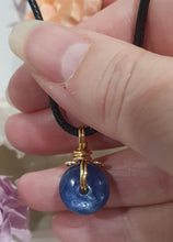 Load image into Gallery viewer, Stunning Blue Kyanite crystal stone donut crystal carving wire wrapped in non tarnish gold wire. Come with a black cork necklace.