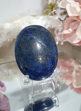 Load image into Gallery viewer, Lapis Lazuli Crystal Palm Stone palm stone on plastic stand. 

INSPIRES HARMONY, WISDOM &amp; PSYCHIC PROTECTION

Lovely Lapis Lazuli Crystal Palm stone with pyrite inclusions on plastic stand. So pretty.  


