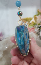 Load image into Gallery viewer, HEART OF THE OCEAN" Handcrafted Titanium Aura Sphalerite Heart Stone Crystal Carving Gold Crystal Energy Enhancer© / Hanger / Ornament / Suncatcher

Inspires PSYCHIC FLOW | LOVE | INTUITION

Gorgeous Titanium Aura Sphalerite heart crystal carving beaded with Aquamarine, Rainbow Hematite &amp; Quartz.  Wire wrapped in gold
