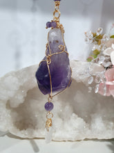 Load image into Gallery viewer, THE MYSTIC AWAKENING" Handcrafted Amethyst Raw Crystal Stone Gold Crystal Energy Enhancer© Hanger Ornament Suncatcher

INSPIRES INTUITION, WISDOM AND SPIRITUALITY

Stunning Raw Amethyst crystal stone beaded with Amethyst and Quartz. Wire wrapped in gold.
