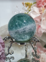 Load image into Gallery viewer, Fluorite Sphere Crystal Carving Stone on Silver Stand

Inspires CONCENTRATION AND STABILITY

Lovely Fluorite Crystal Sphere on silver stand.  super pretty.  Feather fluorite. Amazing pattern.  
