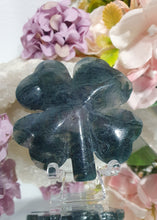 Load image into Gallery viewer, Four Leaf Clover Moss 

Beautiful polished Moss Agate Four Leaf Clover Crystal Carving on plastic stand. Insoires tranquility and grounding. 

HAS A SMALL CRACK on front and a lovely druzy on back
