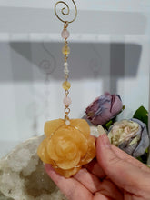 Load image into Gallery viewer, Stunning "ROSE OF SUNSHINE" Handcrafted Orange Calcite Rose Carving gold Crystal Energy Enhancer© Hanger Ornament Suncatcher. hang in your room or space. Inspires Joy, cleansing and love
