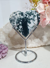 Load image into Gallery viewer, Heart Moss Agate Crystal Carving Stone on stand

INSPIRES GROUNDING AND CONNECTION TO EARTH

Lovely Moss Agate Heart Crystal Carving on silver stand. 
