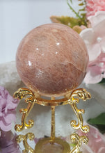 Load image into Gallery viewer, Beautiful Peach Moonstone Sphere Crystal Carving on Gold Stand. Inspires balance and calms.
