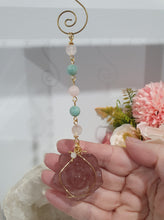 Load image into Gallery viewer, "THE BLUSHING ROSE" Strawberry Quartz Rose Carving gold Crystal Energy Enhancer© Hanger Ornament Suncatcher.

HAPPINESS / LOVE / HARMONY

"THE BLUSHING ROSE - Like the petals of a rose unfolding, The Blushing Rose encourages us to embrace self-love, joy and the beauty within."

Gorgeous Strawberry Quartz Rose Crystal Carving beaded with Ice Pink Malaysian Jade, Rose Quartz, Amazonite and Quartz. Wire wrapped in gold
