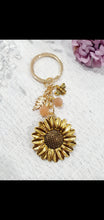 Load image into Gallery viewer, THE SUNFLOWER KEEPER" Metal Sunflower with Sunstone Beads Crystal Keyring.

Choose from Gold of Silver medal colour.

INSPIRES JOY | HOPE | OPTIMISM

Carry a little Sunshine wherever life takes you!

 "The sunflower has long symbolised joy, hope and unwavering optimism. Like the flower that turns towards the sun, it reminds us to keep looking for the light, even through life's difficult seasons".

Gorgeous Metal sunflower Keyring Key ring beaded with AAA sunstone faceted beads.

