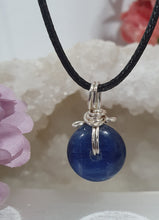 Load image into Gallery viewer, Stunning Blue Kyanite crystal stone donut crystal carving wire wrapped in non tarnish silver wire.  Come with a black cork necklace.
