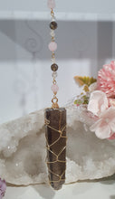 Load image into Gallery viewer, WAND OF STRENGTH" Handcrafted Smoky Quartz Tower Point Stone Gold Crystal Energy Enhancer© Hanger Ornament Suncatcher 

Inspires GROUNDING | LOVE | STABILITY

Gorgeous Smoky Quartz crystal tower beaded with Smoky Quartz, Rose Quartz and Herkimer Diamond.  Wire wrapped in gold
