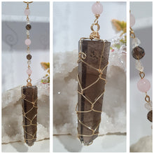 Load image into Gallery viewer, WAND OF STRENGTH" Handcrafted Smoky Quartz Tower Point Stone Gold Crystal Energy Enhancer© Hanger Ornament Suncatcher 

Inspires GROUNDING | LOVE | STABILITY

Gorgeous Smoky Quartz crystal tower beaded with Smoky Quartz, Rose Quartz and Herkimer Diamond.  Wire wrapped in gold
