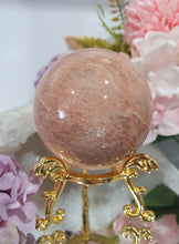 Load image into Gallery viewer, Beautiful Peach Moonstone Sphere Crystal Carving on Gold Stand. Inspires balance and calms.
