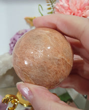 Load image into Gallery viewer, Beautiful Peach Moonstone Sphere Crystal Carving on Gold Stand. Inspires balance and calms.

